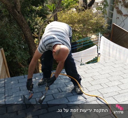 אדם עובד על גג רעפים עם כלי עבודה